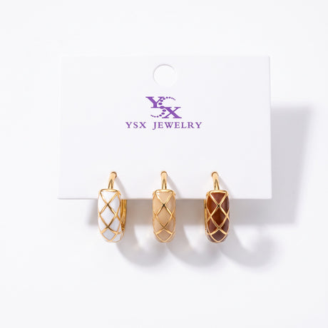 Three single harlequin enamel huggie earrings in white, beige and brown with gold lines