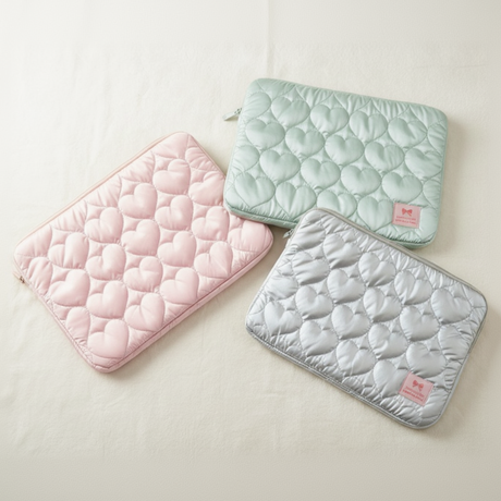Heart print laptop sleeve fabrics in pink, green, and white, flat lay view