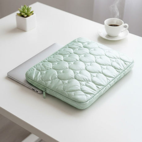 Green quilted heart laptop sleeve styled on a desk with coffee and a plant