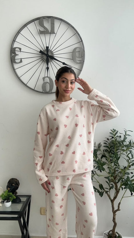 Pink heart print fleece pyjamas worn with a playful salute