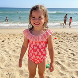Girl wearing a coral heart print swimsuit on the beach