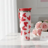 Pale pink travel mug with bold red and white brush stroke hearts and a red lid