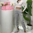 Women's heather grey cuffed sweatpants with a wide elastic waist, worn with hands in the side pockets