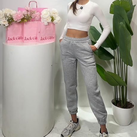 Women's heather grey cuffed sweatpants with a wide elastic waist, worn with hands in the side pockets
