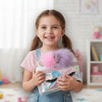 Girl in a pink top holding an iridescent unicorn makeup bag with lash print and fluffy pom ears