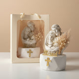 Ivory Holy Family relief beside a cream gift bag and a spray of dried pampas