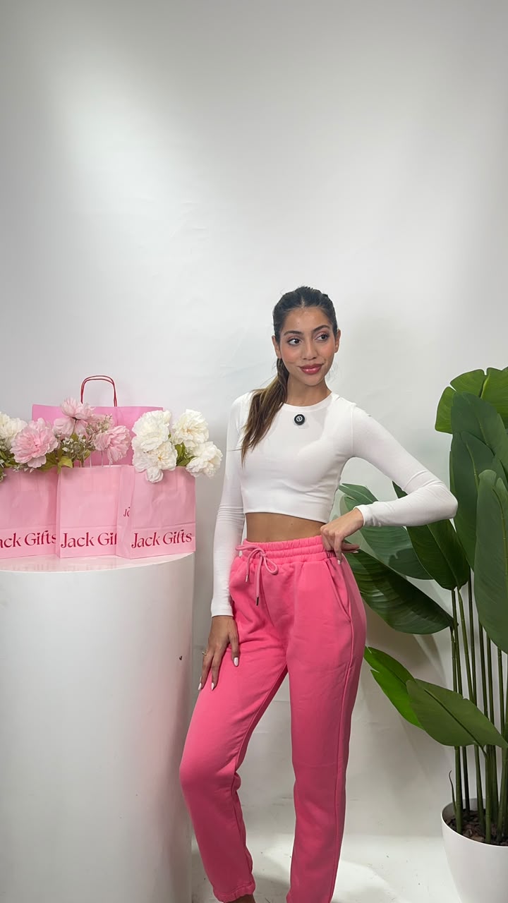Women's hot pink sweatpants with a white drawstring tie at the waist and a hand resting on the hip