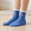 Kids cornflower blue crew socks with white cuffs and a winking Stitch print in pink, worn on feet