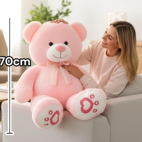 Pink huggable teddy bear with a cream satin bow and heart printed paw pads
