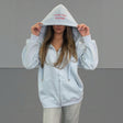 Person wearing a light grey zip jacket with text on the hood against a plain background