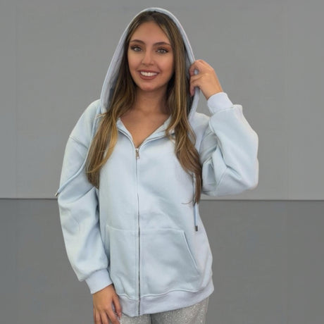 Woman wearing a light blue zip jacket with a hood against a grey background