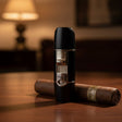 Black cigar lighter with silver accents on a wooden surface, with a blurred background