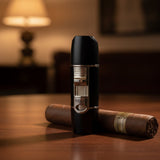 Black cigar lighter with silver accents on a wooden surface, with a blurred background