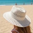 Ivory crochet straw hat with an open stitch crown, seen from behind against the sea