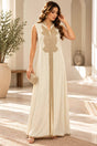 Woman in a long ivory sleeveless kaftan with a gold embroidered front panel in a sunlit room