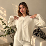 Close view of an ivory knit zip cardigan with ribbed hem and cuffs
