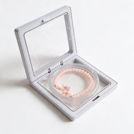 Clear jelly bangle with a peach pink bead bracelet and pink flower charm in a display box