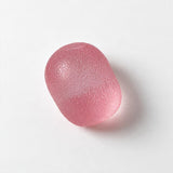 Pink jelly grip egg squishy lying on its side on a white background