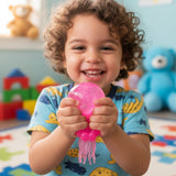 Pink jellyfish-shaped toy held by a hand against a cardboard background