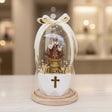 Faceted white base with a gold cross carrying the crowned Infant under ribboned glass