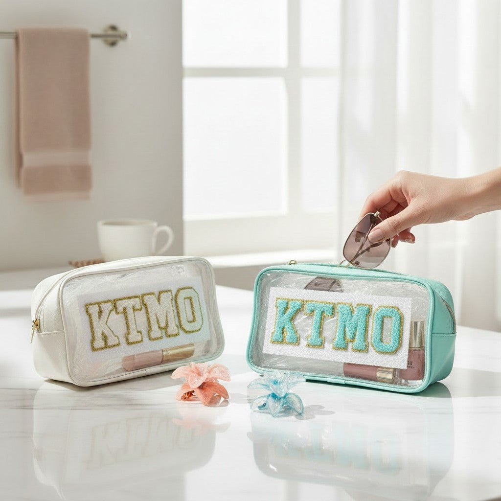 Two clear cosmetic bags with 'KTMO' branding on a bathroom counter