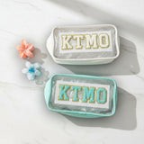 Two small pouches with 'KTMO' text on a white surface with decorative flowers