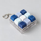 Navy, light blue and white keycap fidget clicker keychain in a clear case