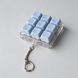 Light blue keycap fidget clicker with nine keys in a clear case and a silver clip