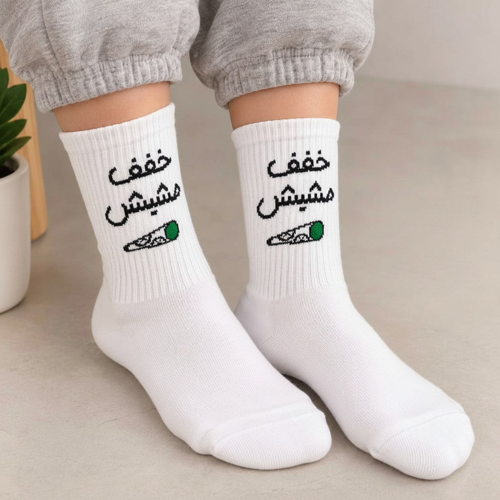 White crew socks with black Arabic lettering and a small green tipped graphic