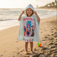 Child wearing a colorful hooded towel on a beach