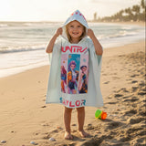Child wearing a colorful hooded towel on a beach
