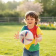 Child catching the white football printed with red and blue swirl graphics