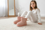 Pink plush winter boots worn with white leggings on a soft rug