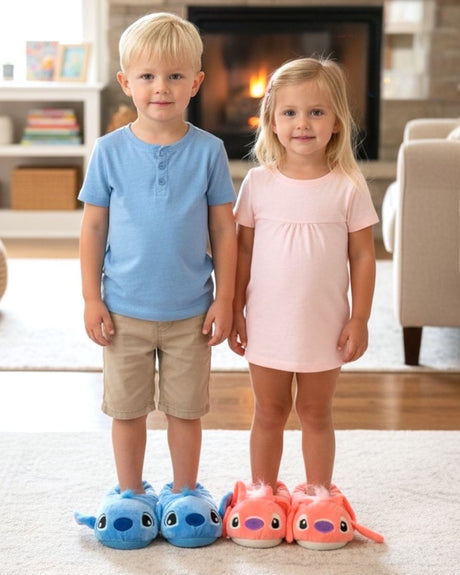 Boy in blue and girl in pink plush animal slippers standing on a rug by a fireplace
