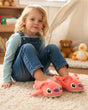 Young girl sitting on a rug wearing fluffy pink character slippers in a playroom