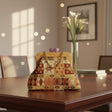 Handmade kilim frame bag with a wooden top and purple clasp on a dining table