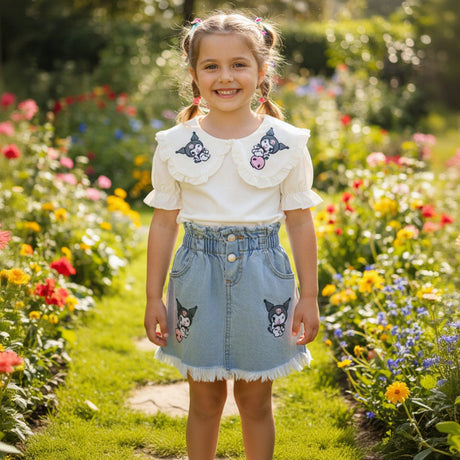 Close view of a cream Kuromi collar top and frayed hem denim skirt with pink skull motifs