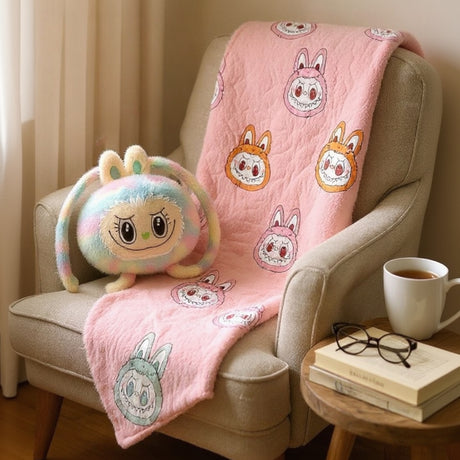 Pink fleece blanket with character prints draped on an armchair