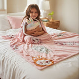 Girl on a bed with a pink character print blanket and plush bag