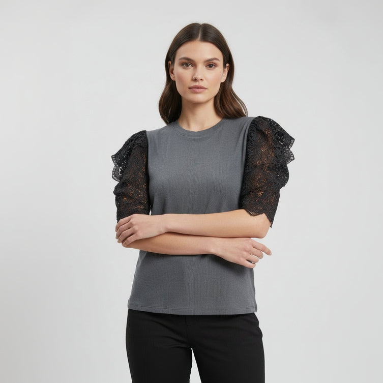Grey top with black lace sleeves, arms folded