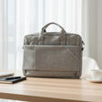 Gray laptop bag in a home office setting with a notebook and cup