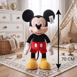 Large standing cartoon mouse plush in black, red and yellow on a patterned rug
