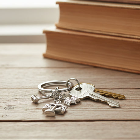 Law keychain with gavel, scales of justice, and law book charms beside books