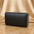Black leather clutch bag with metallic accents on a beige fabric background