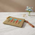 Jute zip pouch embroidered with three turquoise tulips on black stems and red leaf spears