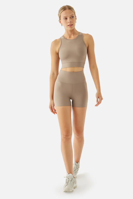 Woman wearing a beige athletic biker outfit on a white background