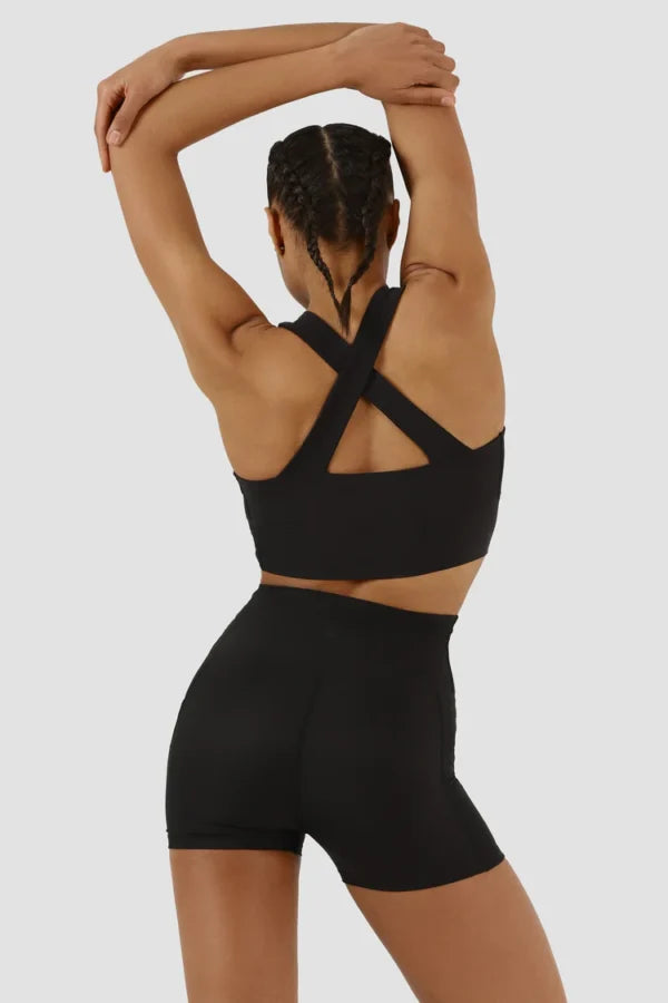 Person wearing a black sports bra and shorts on a plain background