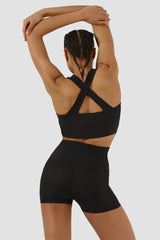 Person wearing a black sports bra and shorts on a plain background