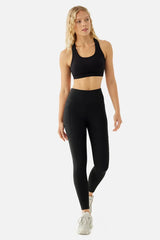 Woman wearing a black sports bra and leggings on a white background