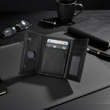 Black leather wallet with card slots on a dark surface with glasses, mug, and pen.